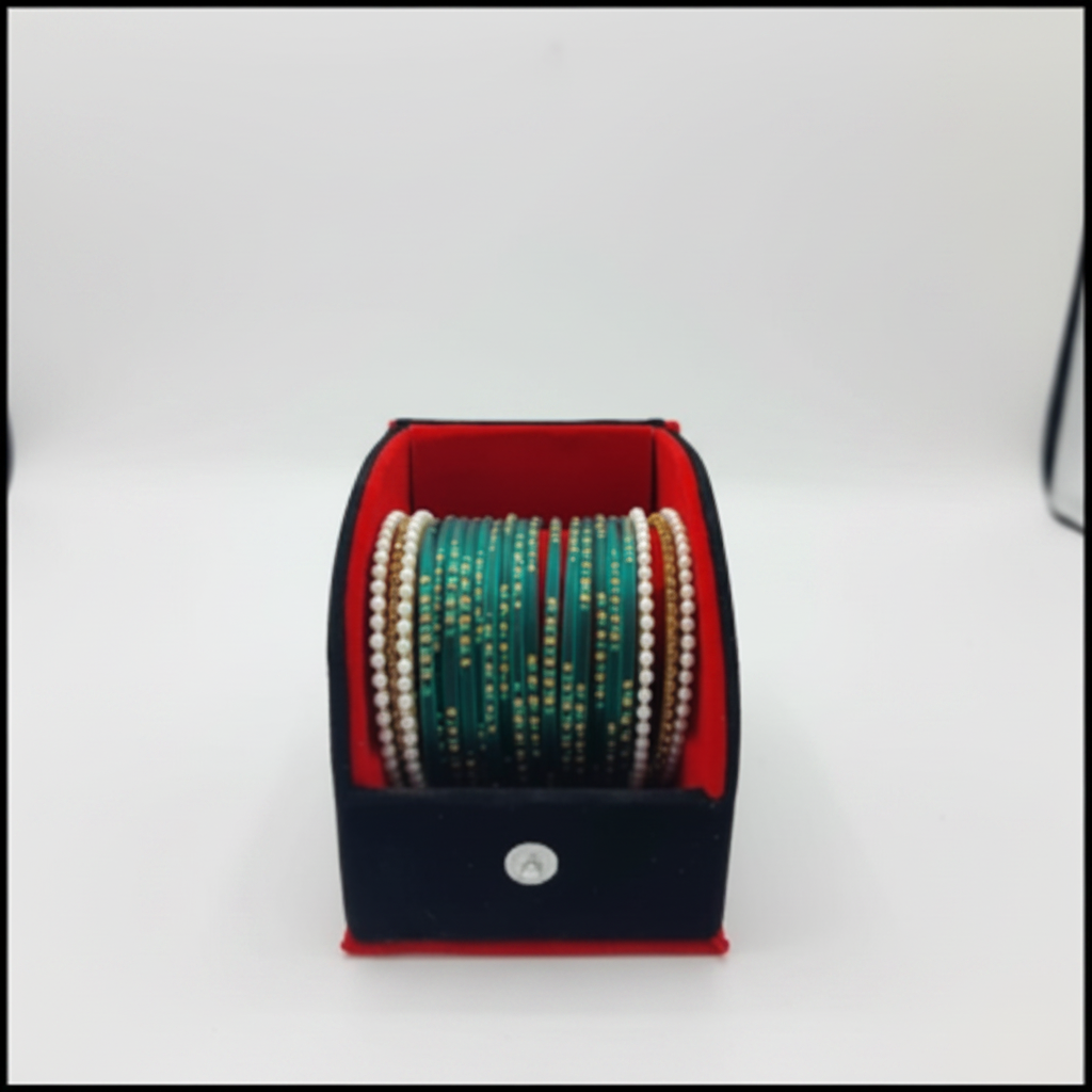 A set of Indian bangles (buckles) displayed in an open black jewelry box with a red interior. The bangles feature green, white, and gold metallic designs.